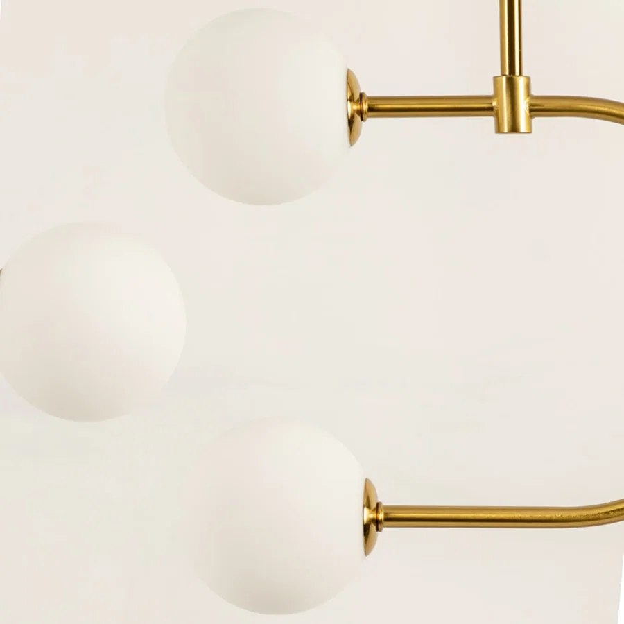 Gold metal pendant light closeup showcasing smooth white glass globes and refined modern decorative detailing.