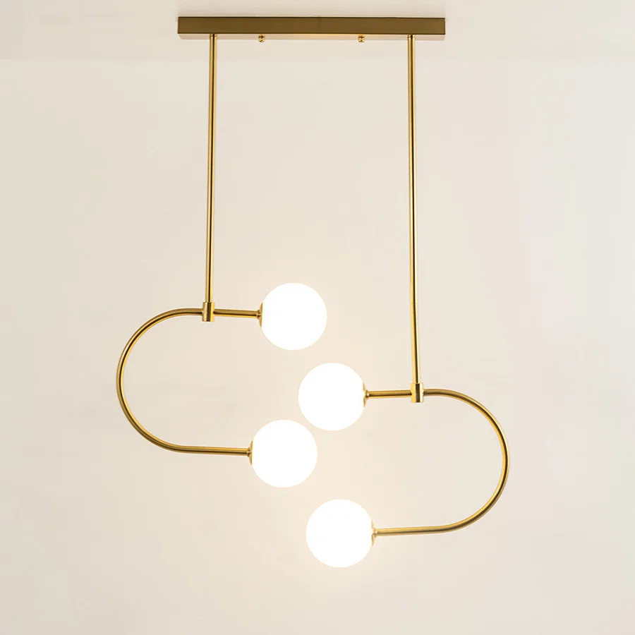 Modern gold metal ceiling light with white glass globes and curved frame emitting soft glow ideal for dining or living room decor.
