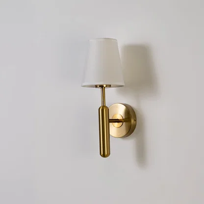 Gold metal wall light with white fabric shade displayed on a white background with light off highlighting its sleek minimal contemporary form.
