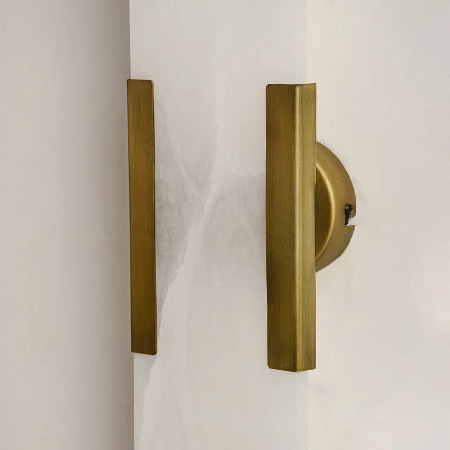 Closeup of white marble and gold metal wall light for elegant hallway and luxury decor styling spaces.