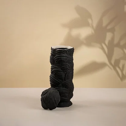 Modern handcrafted black ceramic vase with unique spiral pattern shown on white background perfect for minimalist interior decoration.