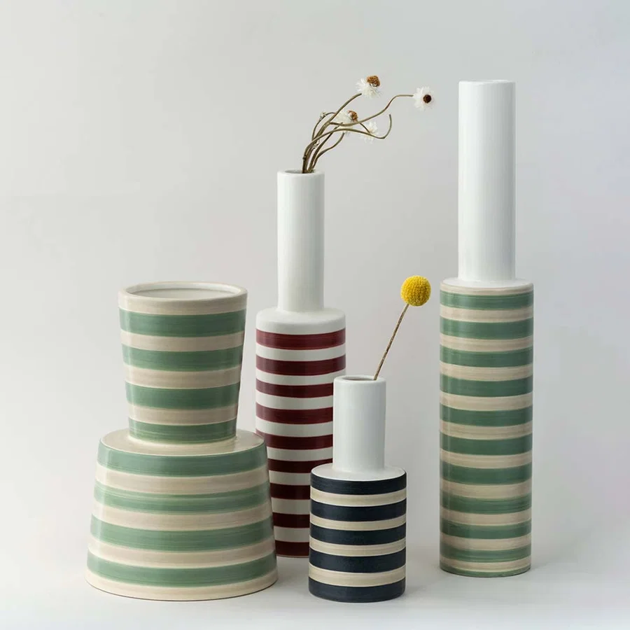 A slim striped vase shown in a clean styling setup highlighting its modern form and soft green pattern making it ideal for grouping with contemporary decor pieces.