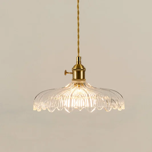Illuminated clear patterned glass pendant light with gold fittings creating soft ambient lighting indoors.