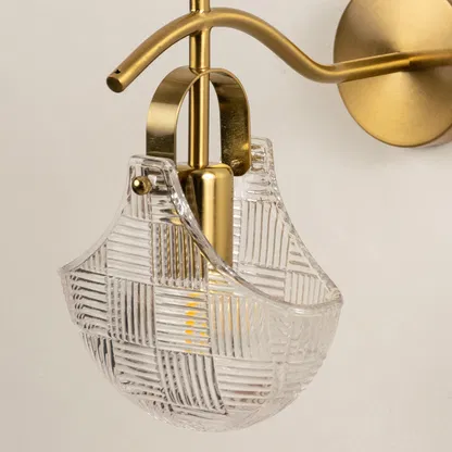 Closeup of gold metal wall light with textured glass shade highlighting detailed pattern and elegant finish for modern wall decor styling.
