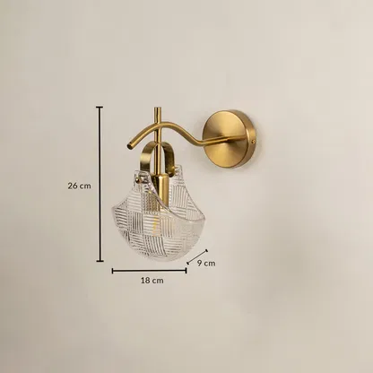 A gold wall sconce with a patterned clear glass shade shown with full measurements displaying a height of 26 cm a width of 18 cm and a depth of 9 cm for precise placement.