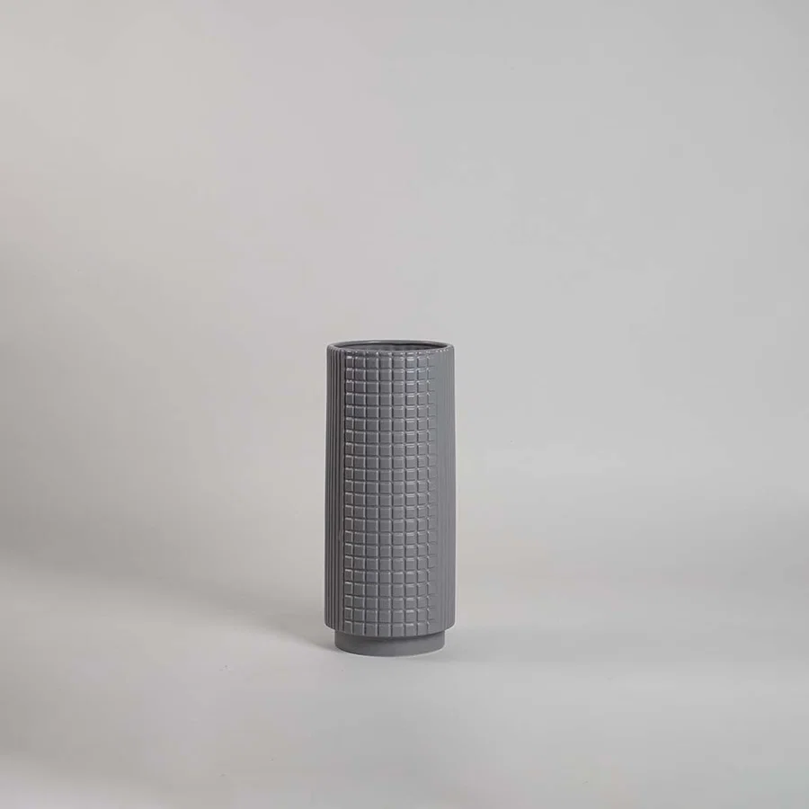 Grey grid textured ceramic cylinder vase with a stepped base profile on white background for contemporary interior styling.