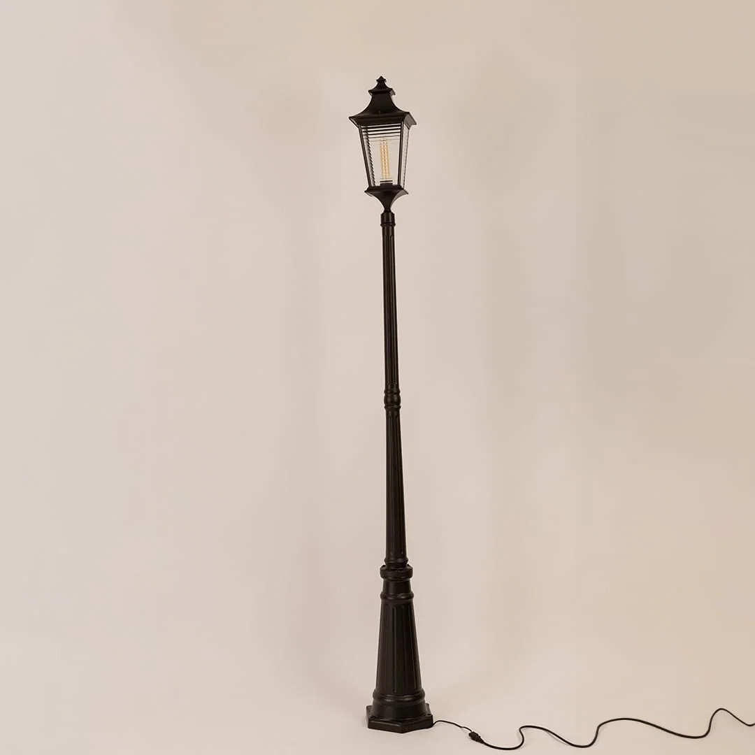Black metal outdoor lamp post with clear glass lantern displayed on white background with light off for product detailing.