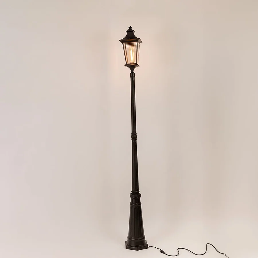 Black metal outdoor lamp post with illuminated clear glass lantern shown on white background for exterior decor display.