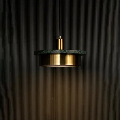 Green marble and metal disc pendant light hanging against dark textured wall with light on for stylish modern décor.
