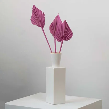 Pink dried palm leaves in white vase styled for modern home table decor and boho interior decoration.