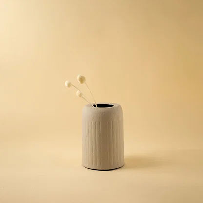 Minimalist beige cylindrical vase with dried bud stem for clean modern home decor and stylish shelf display accents.