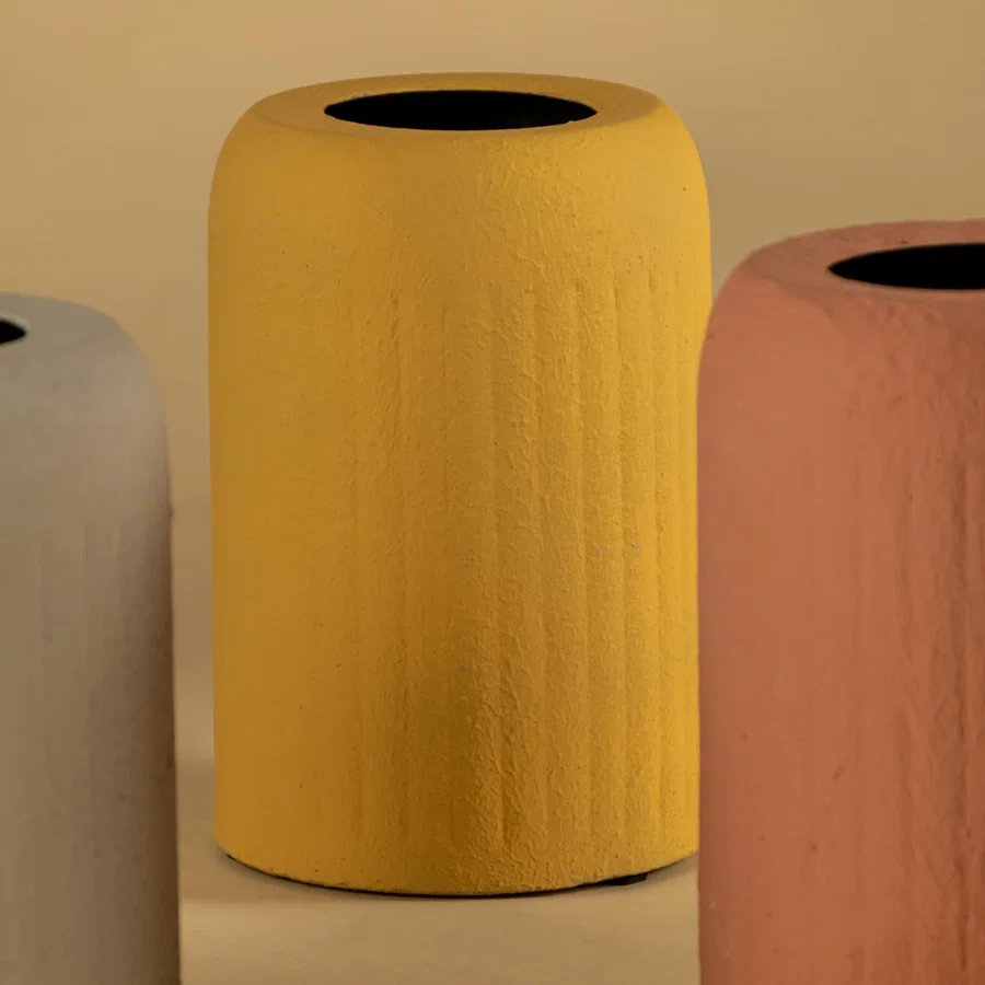 Detailed view of ribbed texture on vibrant yellow metal cylindrical vase for modern home decor and shelf styling.