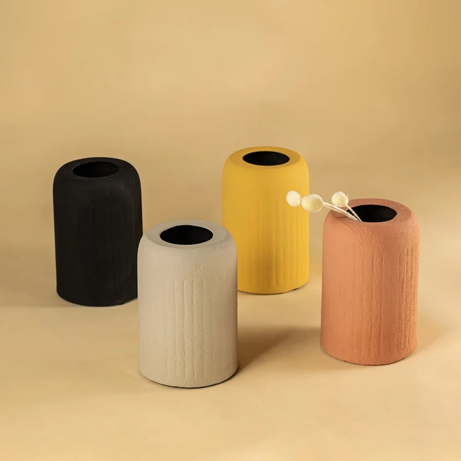 Set of four textured cylindrical metal vases in neutral tones for modern home decor and artistic tabletop display.