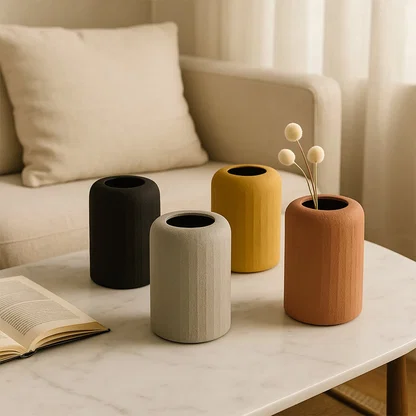 Four colorful cylindrical metal vases with dried buds on marble table for modern living room home interior decor.