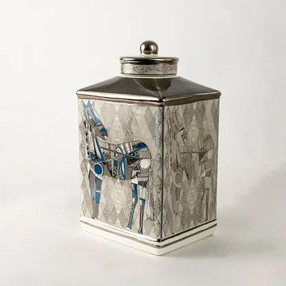 Grey ceramic decorative jar with blue floral artwork and silver lid for sophisticated shelf styling and home decor.