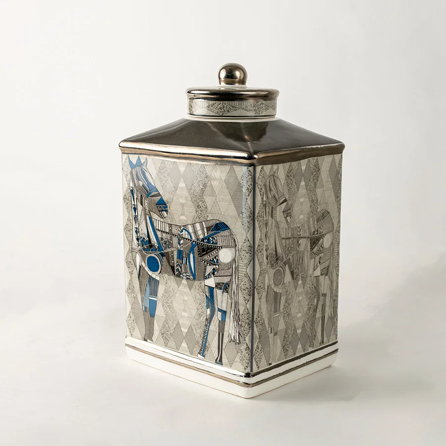 Grey ceramic decorative jar with blue floral artwork and silver lid for sophisticated shelf styling and home decor.