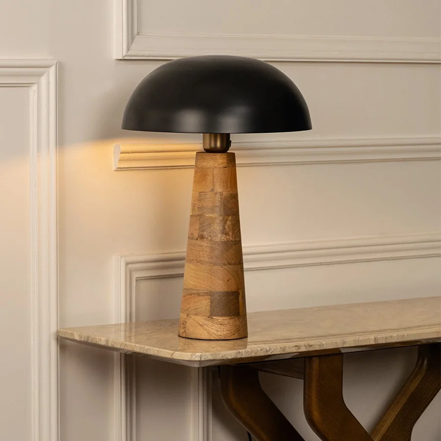 Black dome shade wooden cone table lamp on marble shelf with light on for artistic modern décor.