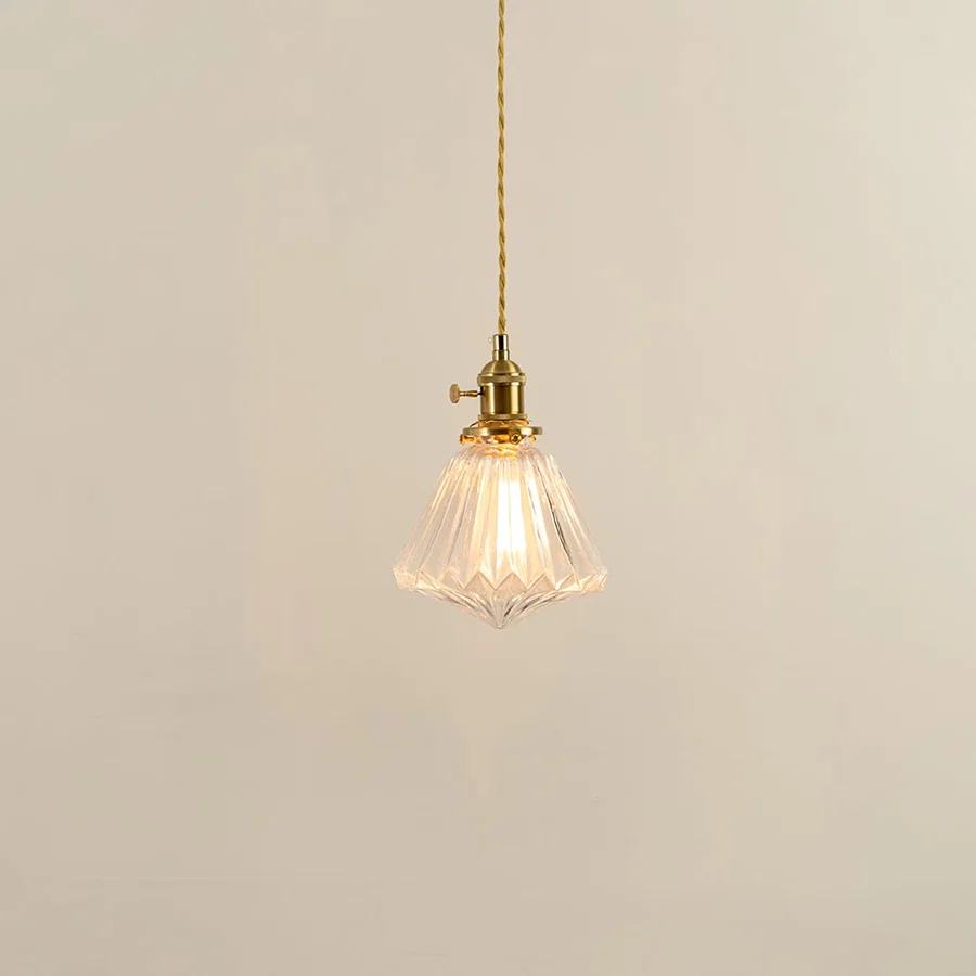 Clear textured glass and brass metal pendant light with warm illumination for modern decor spaces.