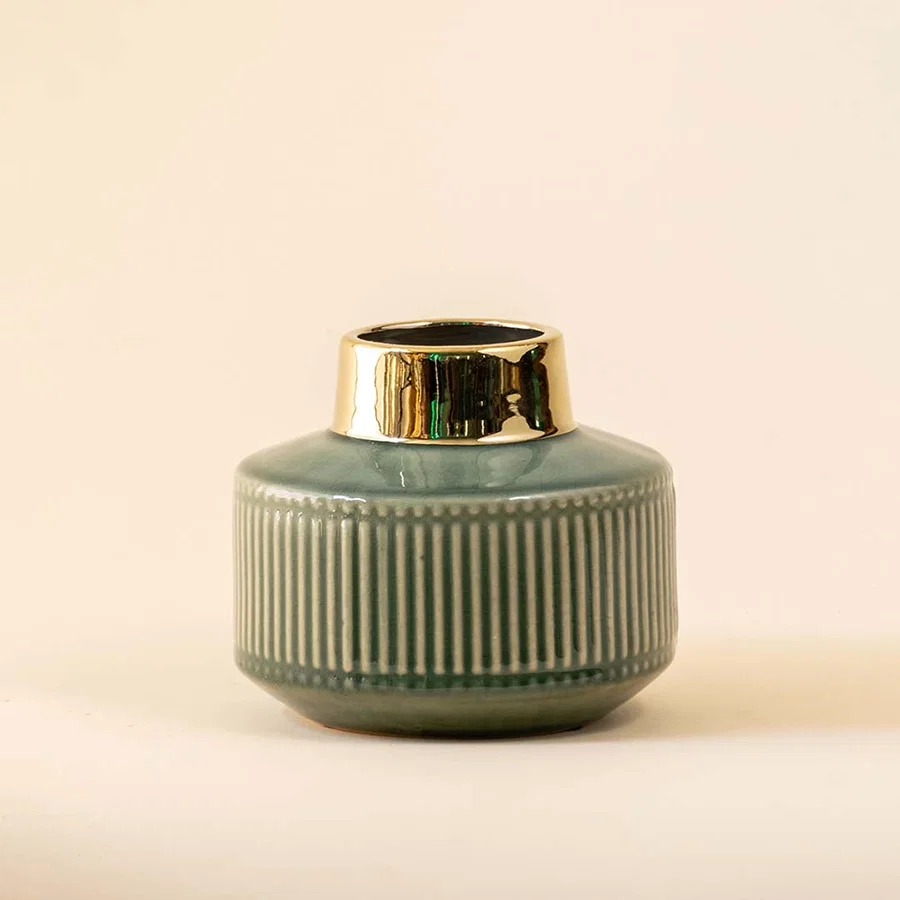 Green ribbed ceramic decorative jar with gold rim displayed on white background adding elegant accent for shelf or tabletop decor.