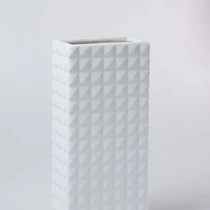 Closeup of the white textured ceramic vase showing its raised geometric pattern and smooth finish for modern minimal home styling.