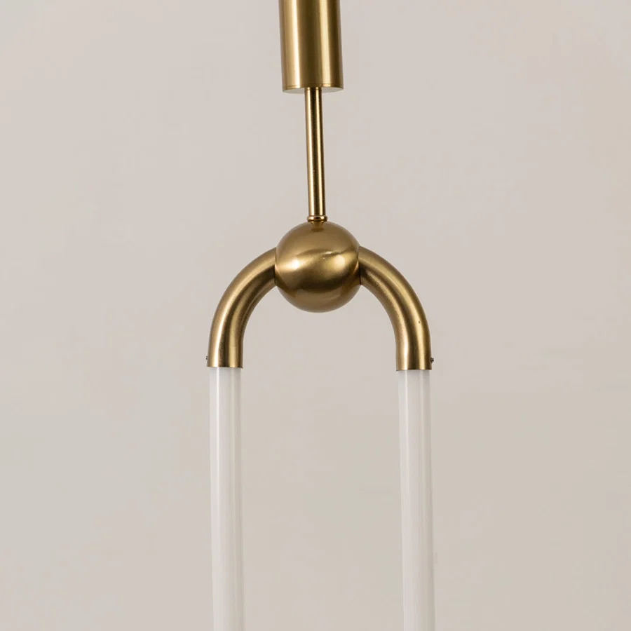 Closeup of gold metal pendant light with curved frame and glass shades on white background perfect for modern lighting decor.