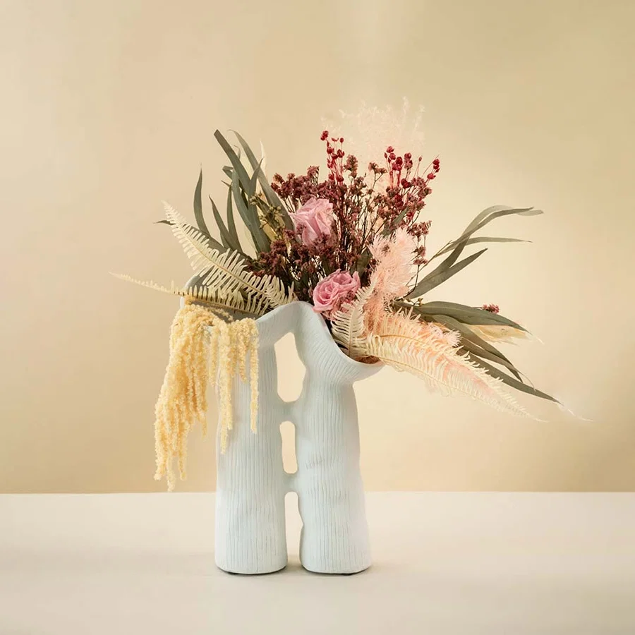 Modern white ceramic vase featuring fluid sculptural shape and minimalist ribbed texture for elegant interior styling.