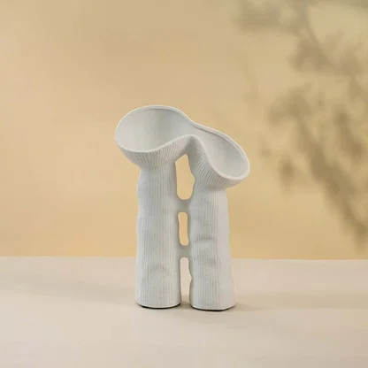 Modern minimalist white ceramic vase featuring creative sculptural curves and twin openings in matte finish against white background.