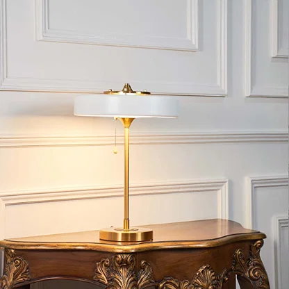 White modern table lamp with gold stand illuminated on a clean white background highlighting its sleek contemporary design.