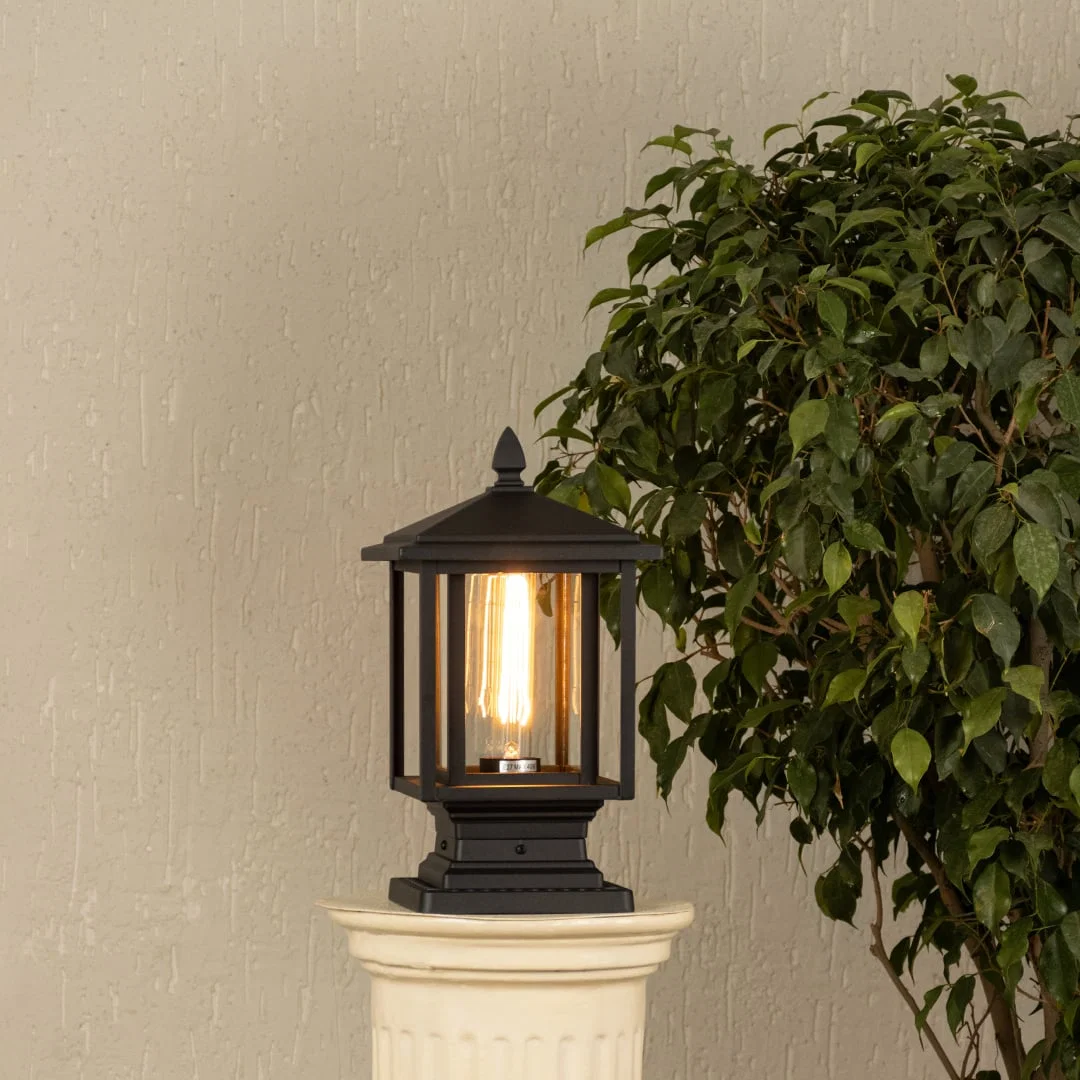 Black metal outdoor post light with ribbed glass Light On placed on a decorative column Lifestyle image patio decor.