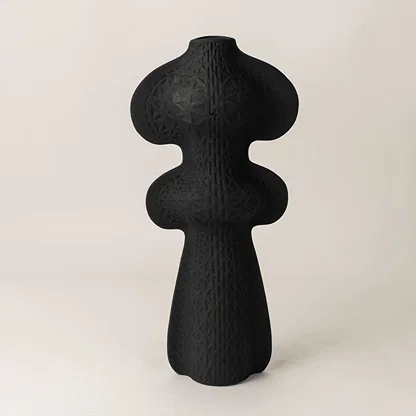 Black ceramic decorative vase with abstract organic silhouette for modern shelf styling and artistic home decor.