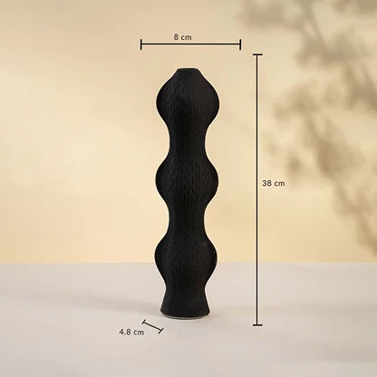 Black sculptural vase displayed on a neutral surface measuring 38 cm in height 8 cm in width and 4 cm in base diameter.