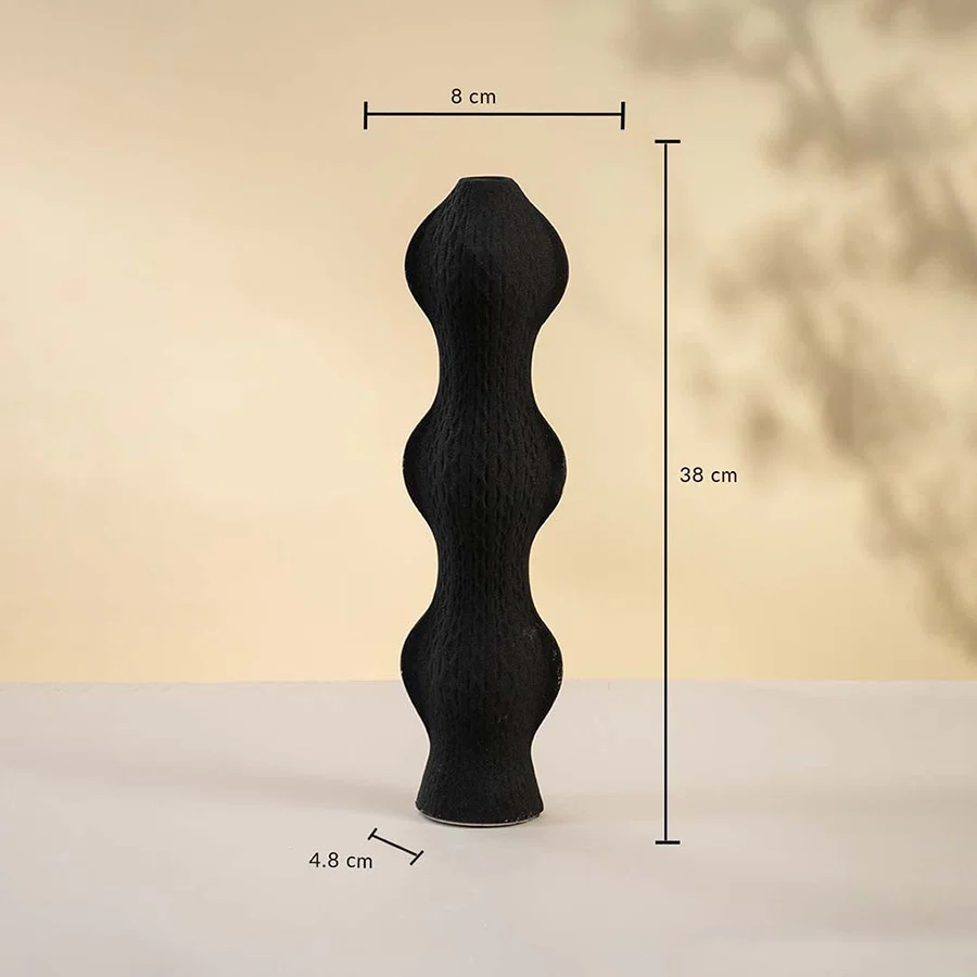 Black sculptural vase displayed on a neutral surface measuring 38 cm in height 8 cm in width and 4 cm in base diameter.