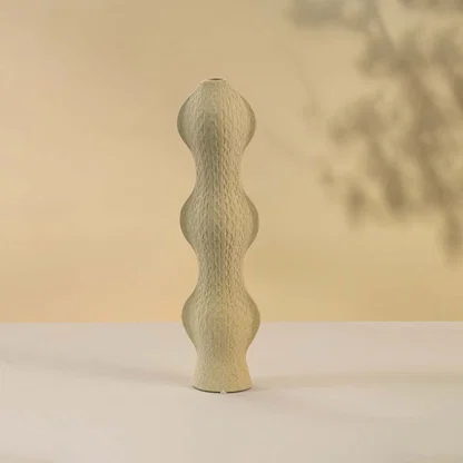 Contemporary beige ceramic vase with curved silhouette and textured surface against white background perfect for adding sophistication to modern home interiors.