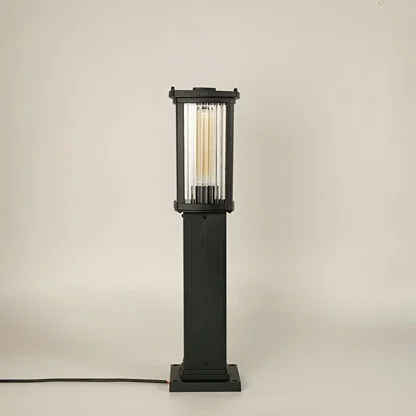 A modern black outdoor bollard light shown on a white background with the light off highlighting its clean rectangular structure clear ribbed glass panels and sturdy base.