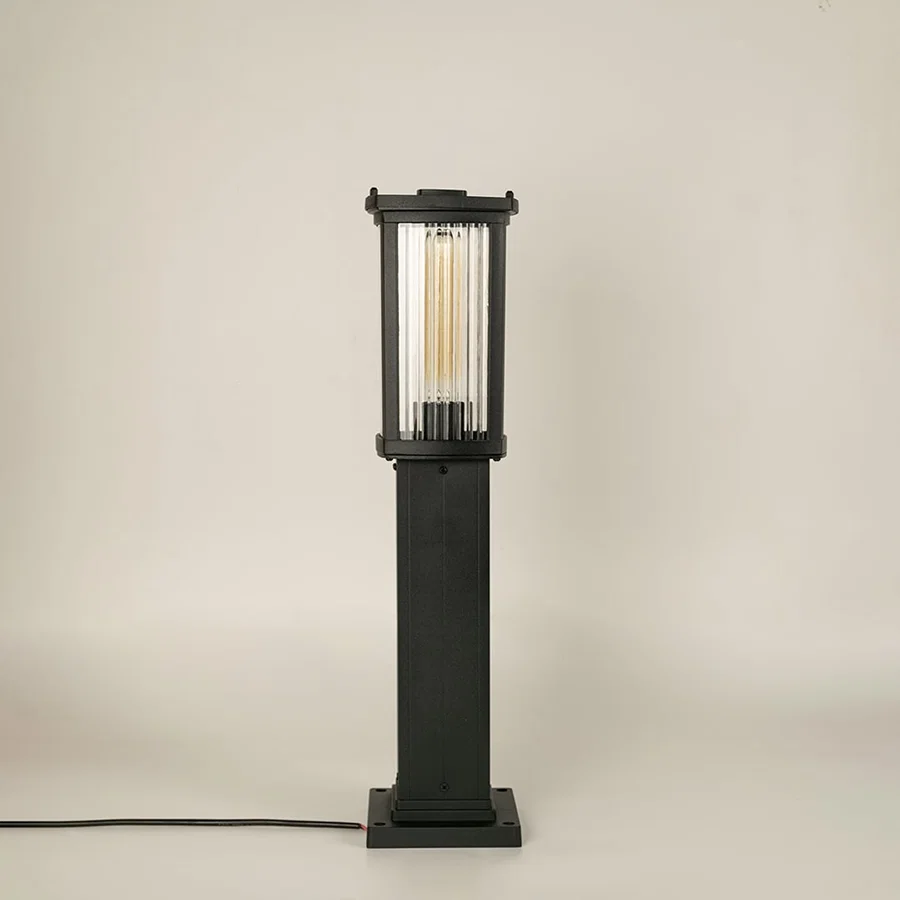 A modern black outdoor bollard light shown on a white background with the light off highlighting its clean rectangular structure clear ribbed glass panels and sturdy base.