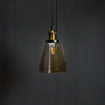 Gold glass pendant light with brass and black holder in stylish design turned off against black background.
