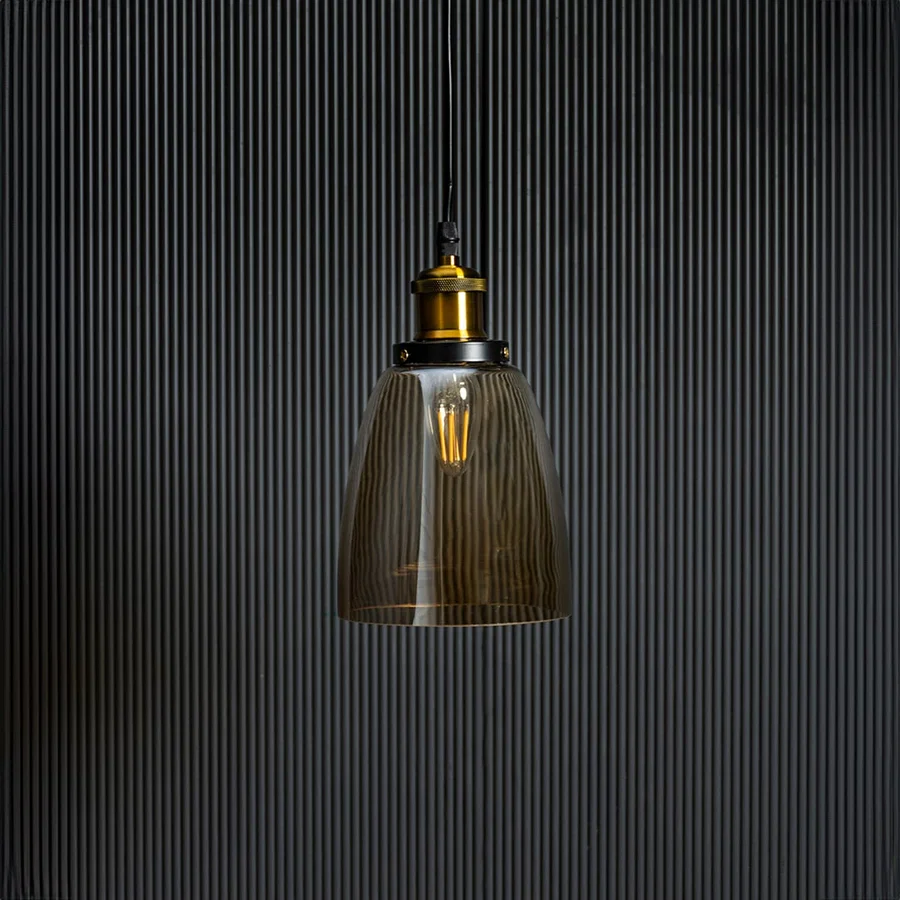 Gold glass pendant light with brass and black holder in stylish design turned off against black background.
