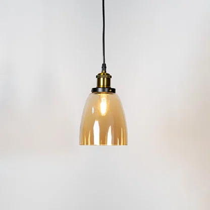 Smoked glass pendant light illuminated with warm glow and brass metal accents for stylish ceiling lighting decor.