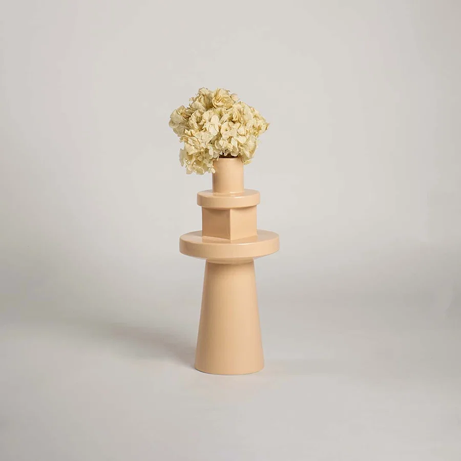 Front view of the nude colored stoneware flower pot with sculptural totem shape isolated on a plain white studio background setting.