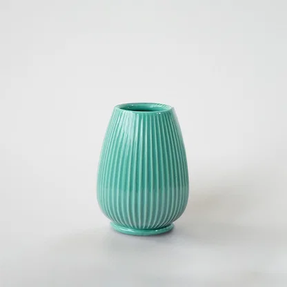Mint green ceramic decorative vase with ribbed texture for tabletop styling and elegant modern home decor displays.