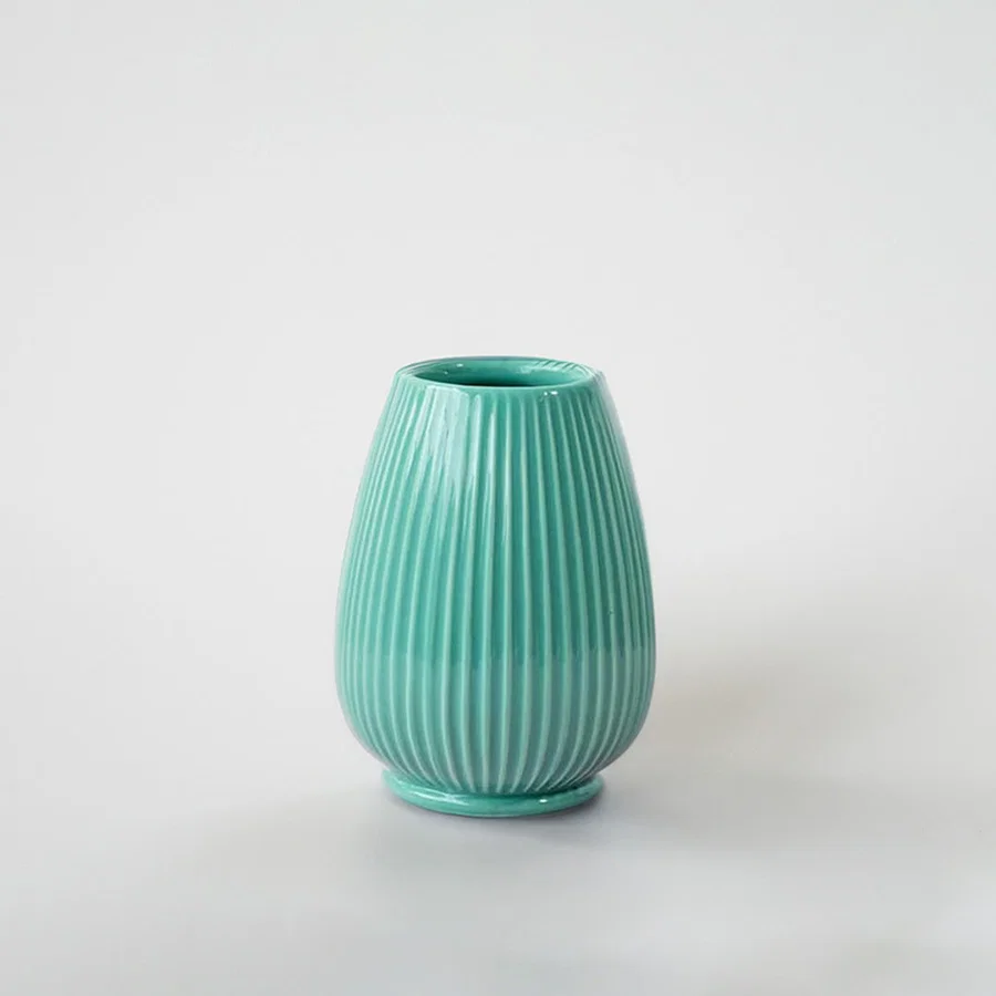 Mint green ceramic decorative vase with ribbed texture for tabletop styling and elegant modern home decor displays.