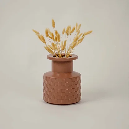 Brown ceramic vase with geometric texture styled beside dried flowers brings organic charm to living room decor.