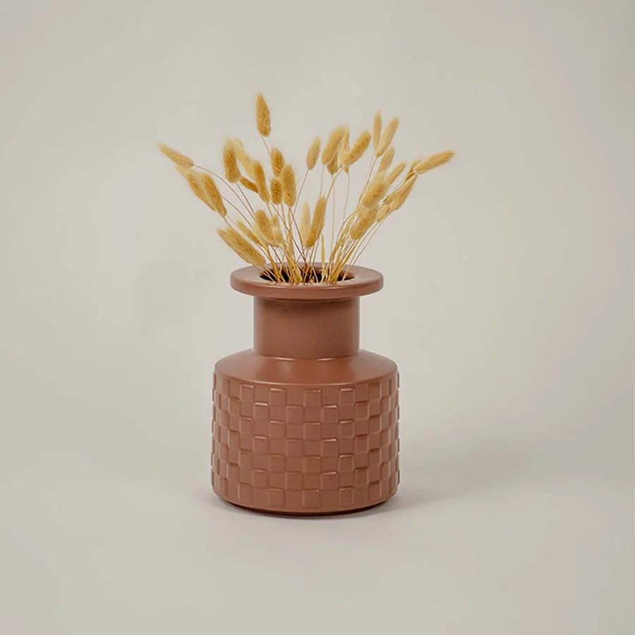 Brown ceramic vase with geometric texture styled beside dried flowers brings organic charm to living room decor.