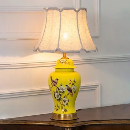Yellow floral ceramic table lamp with scalloped fabric shade creating warm traditional ambient lighting on a wooden console table.