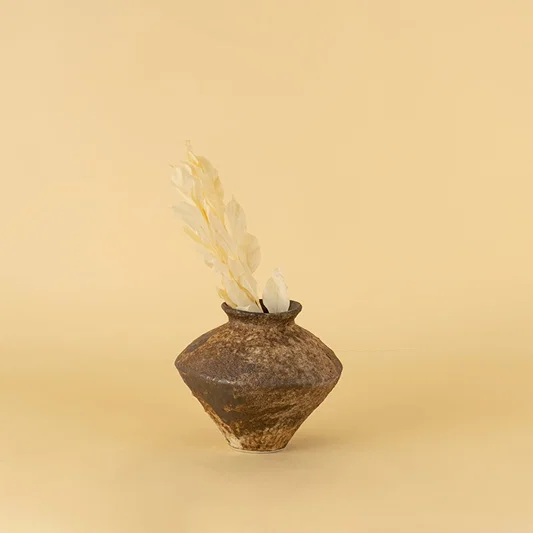 Rustic brown ceramic vase with textured finish styled on wooden table adding earthy elegance to home interior decor