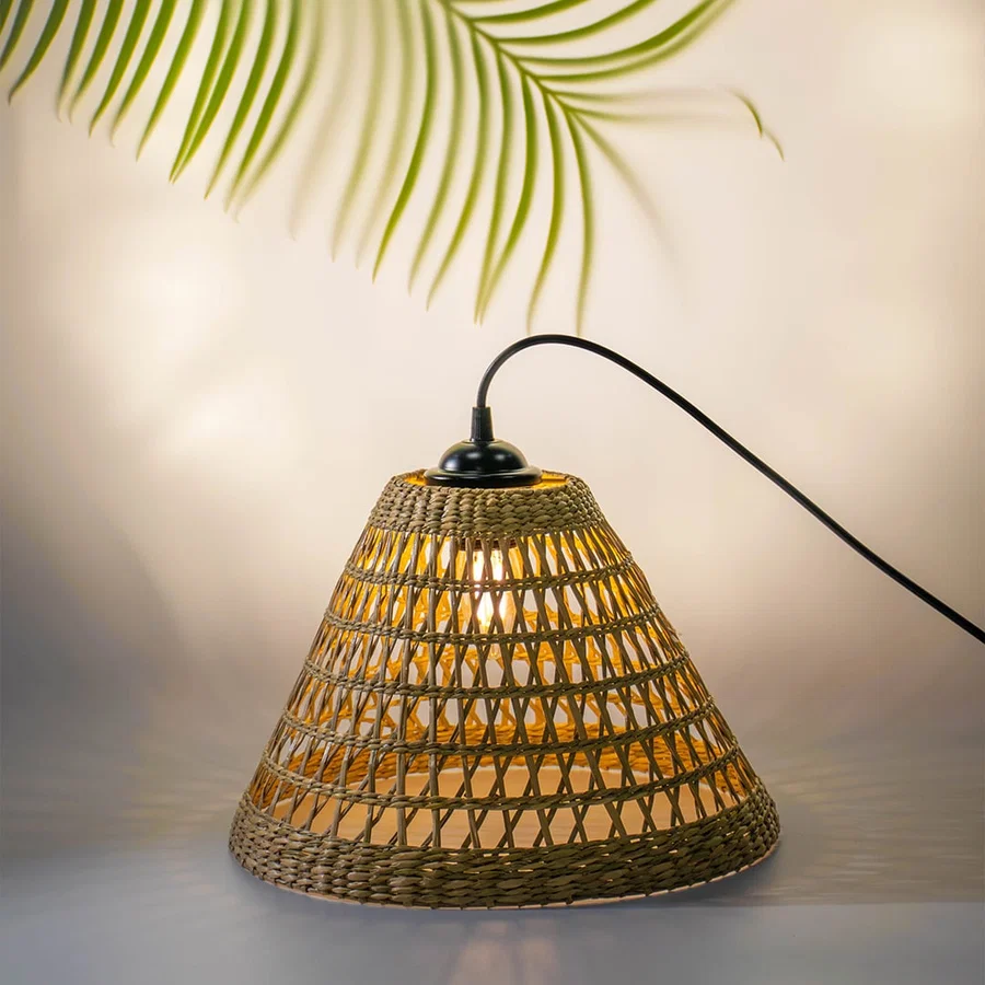 Handwoven rattan table lamp with black curved arm creating warm bohemian lighting and natural charm.