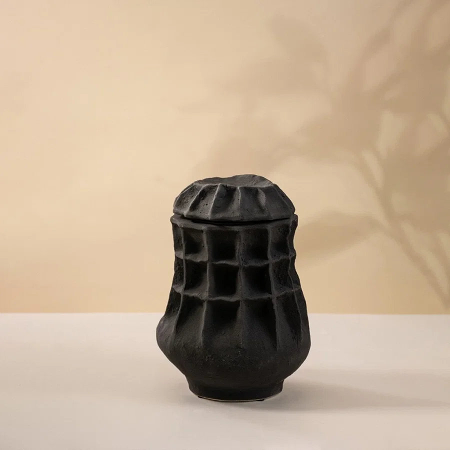 Matte black ceramic vase displayed on a white background highlighting detailed craftsmanship and modern artistic form.