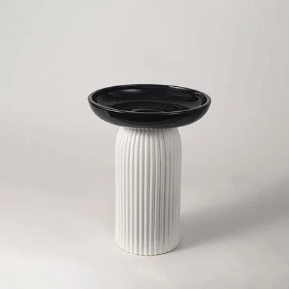 A modern black and white decorative pedestal bowl displayed on a clean white background highlighting its sleek sculptural design for interiors.