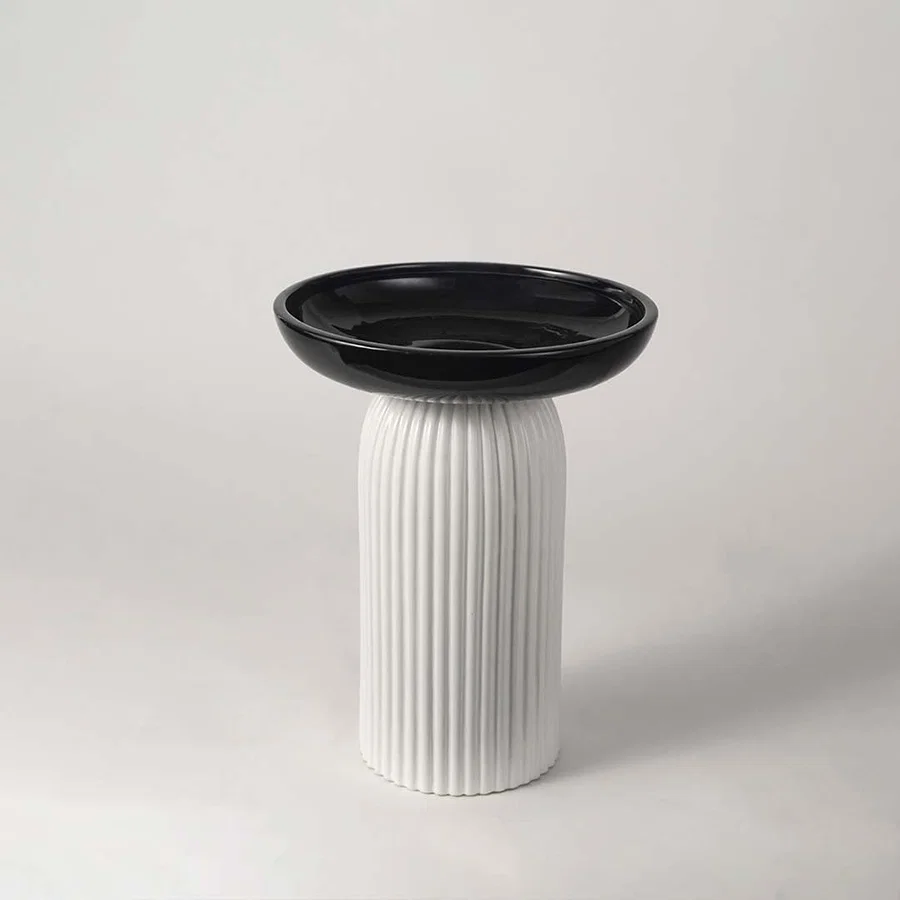 A modern black and white decorative pedestal bowl displayed on a clean white background highlighting its sleek sculptural design for interiors.
