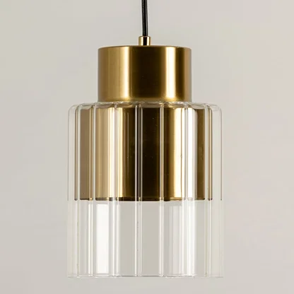Gold metal pendant light with clear glass shade illuminated to display elegant modern ceiling lighting design.